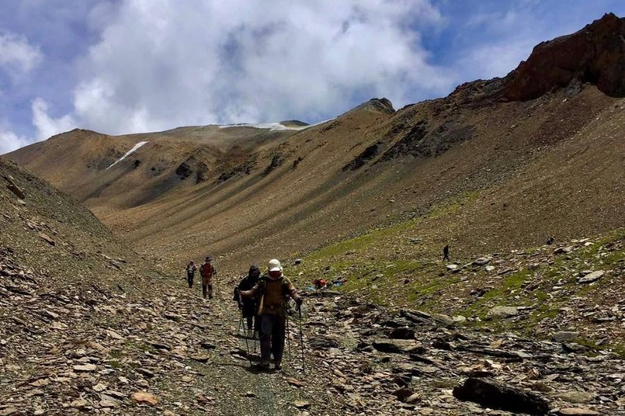Trekkers ascending rocky slope in high-altitude desert landscape of Upper Dolpo
